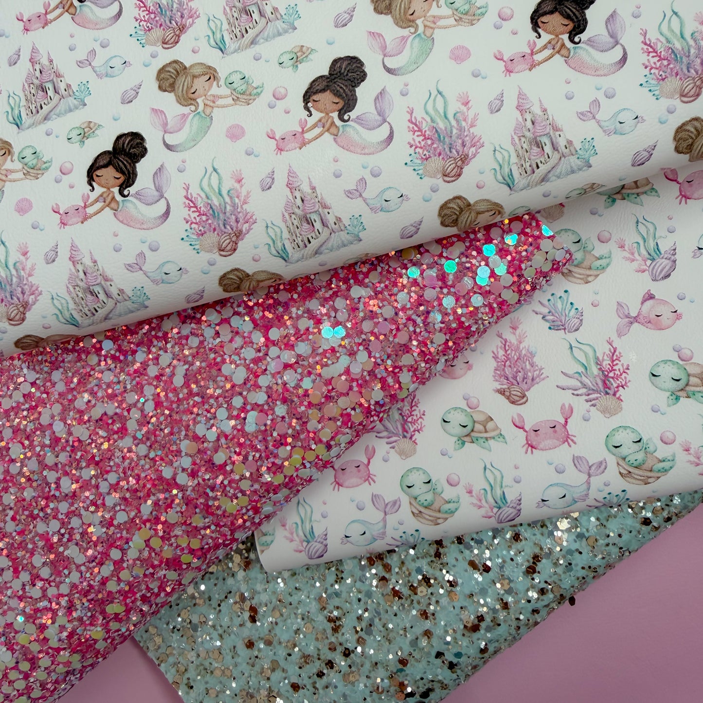 Fabric with mermaid and sea creature patterns and glittery pink and turquoise fabric.